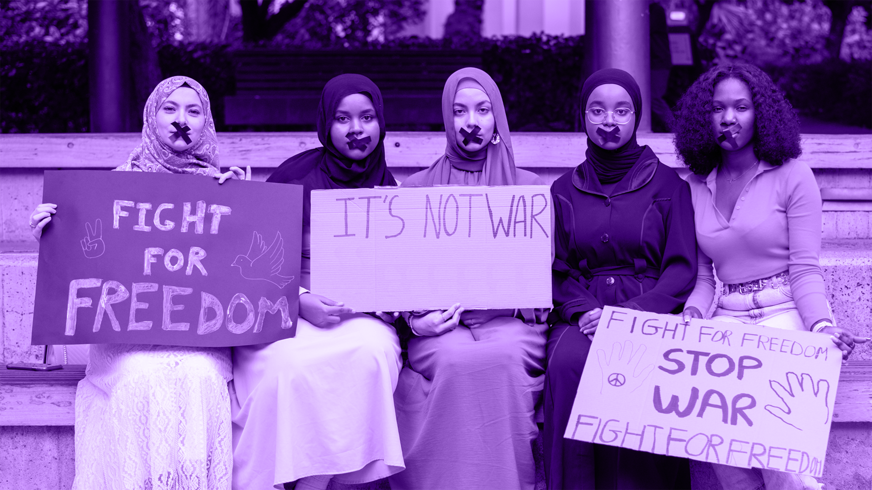Women holding signs that read fight for freedom and it's not war